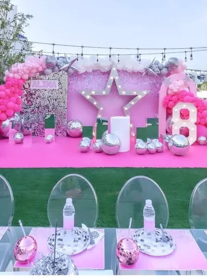 A fun and vibrant Barbie Disco party for an 8th birthday. The setup is an explosion of pink, with a shimmer wall, a light-up star, and disco ball accents.