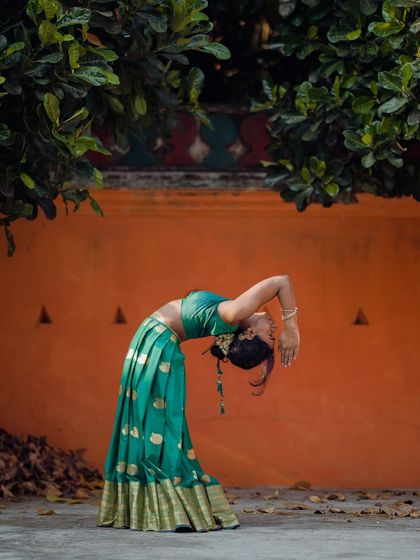 A traditional yoga shoot, capturing a standing backbend in a beautiful green lehenga.