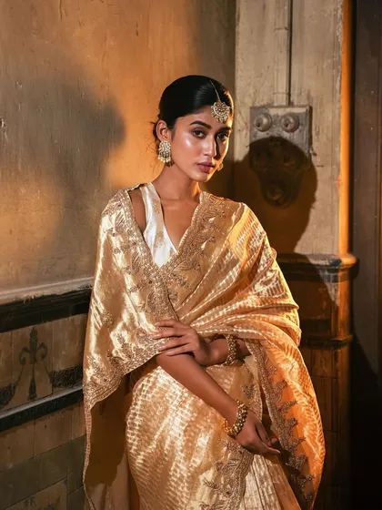 Bathed in golden light, this heirloom-worthy saree is a testament to classic weaves and timeless beauty. The intricate border and lustrous fabric make it a piece to be cherished forever.