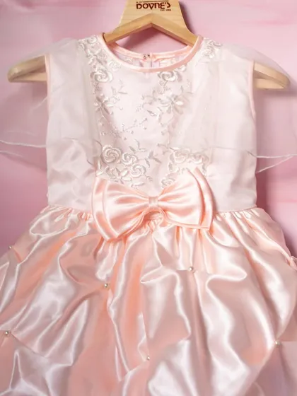 This peach satin dress is pure elegance. I designed it with a beautifully embroidered bodice, sheer capelet sleeves, and a full, gathered skirt dotted with pearls for a truly luxurious feel.