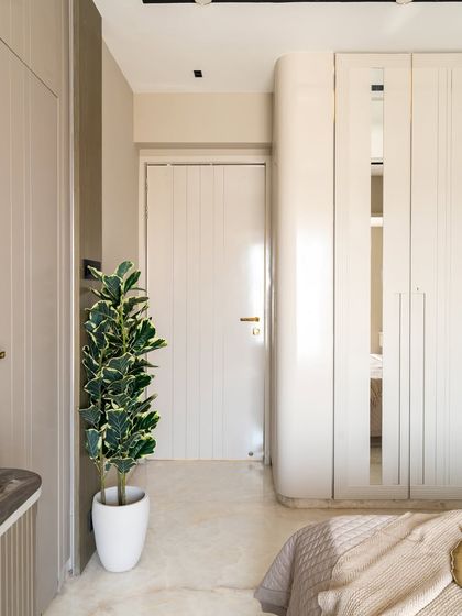 This bedroom is a masterclass in modern design, defined by clean lines, soft neutrals, and striking copper accents that bring an unexpected touch of glam. The ribbed textures on the wall add subtle depth, while curated decor pieces and lush greenery breathe life into the space.