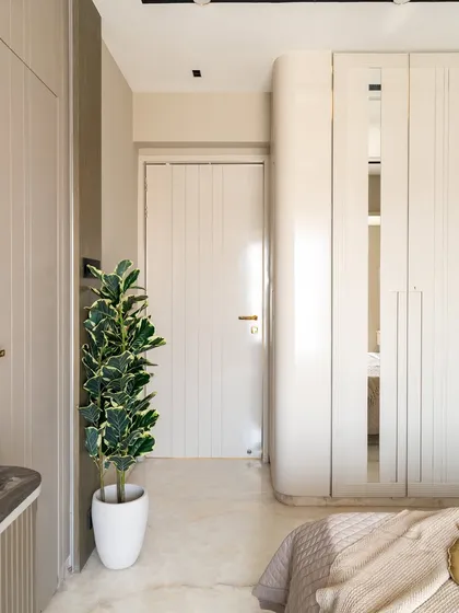 This bedroom is a masterclass in modern design, defined by clean lines, soft neutrals, and striking copper accents that bring an unexpected touch of glam. The ribbed textures on the wall add subtle depth, while curated decor pieces and lush greenery breathe life into the space.