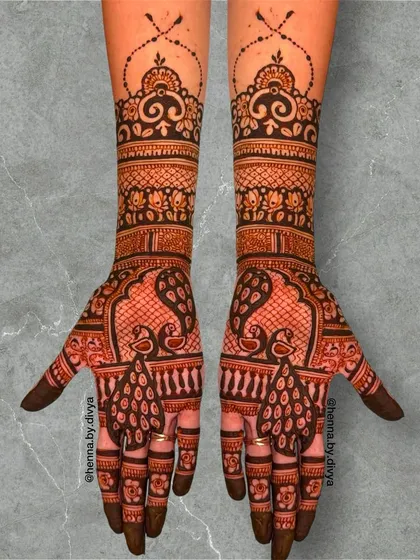 A classic symmetrical bridal design featuring two peacocks facing each other. The arms are covered in detailed bands of traditional patterns, creating a very full and rich look.