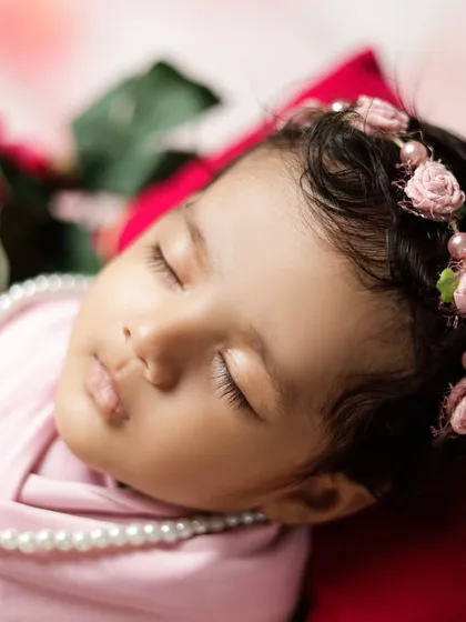 A detailed close-up of a newborn's face, showing her delicate eyelashes and serene expression. These are the simple, beautiful features we love to capture.
