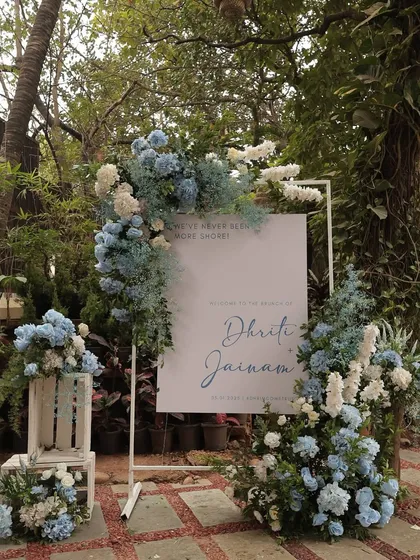 A chic welcome sign for a pastel blue brunch. The sign is framed by a beautiful arrangement of blue and white hydrangeas, setting a sophisticated and dreamy tone for the event.