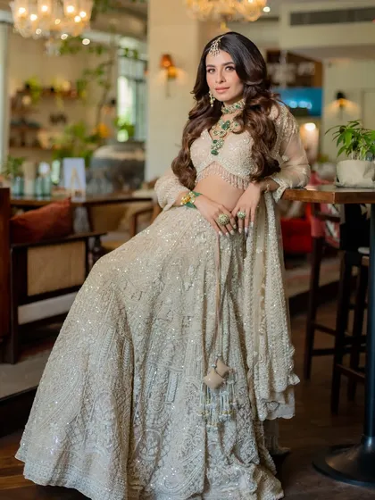 This pose highlights the beautiful drape of the ivory lehenga and the way it complements the bride's silhouette, creating a look of effortless grace.