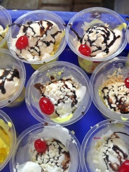 Individual cups of ice cream sundae, garnished with chocolate sauce and a cherry. This is a simple yet delightful dessert option that is loved by guests of all ages.