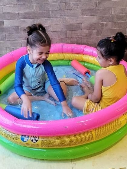 Friends sharing a laugh in the rainbow pool. Our Holi parties are a great way for kids to socialize and celebrate together.