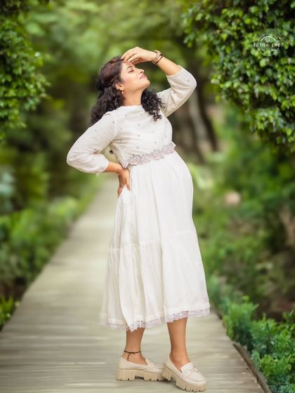 A beautiful solo outdoor portrait, with the mom-to-be basking in the sunlight in a lovely white traditional dress.