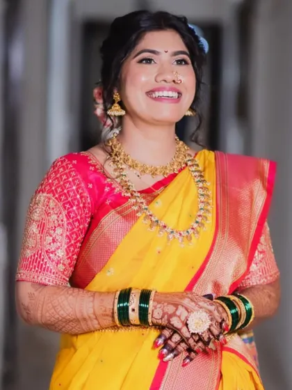 A happy bride in a yellow saree. The makeup is fresh and glowing, with a simple hairstyle adorned with flowers.