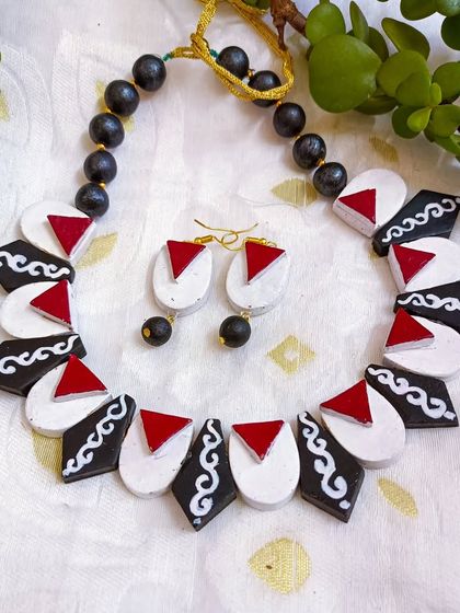 A beautiful and stylish fusion necklace. The design combines different geometric shapes and patterns in a classic black, white, and red palette.