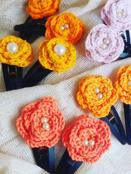 My collection of floral hair clips. These beautiful accessories feature colorful crochet flowers with pearl centers, perfect for adding a touch of elegance to any hairstyle.