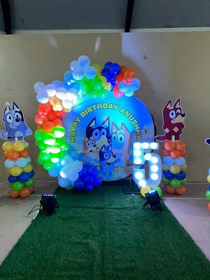 It's a Bluey party! I created this fun and colorful setup for Anushka's 5th birthday, featuring the whole Heeler family. The backdrop was surrounded by bright balloons and character stands, with a green turf walkway leading to the celebration.