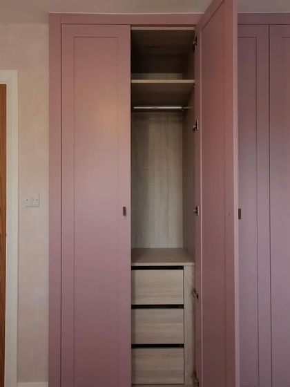 Another interior view of the pink wardrobe, showcasing the hanging rail and drawer combination. This practical layout ensures that there is a designated space for every type of clothing, keeping the room tidy and organized.