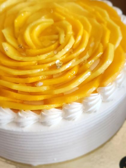 A mouth-melting Fresh Mango Cake, with the top covered in thinly sliced mangoes arranged in a beautiful floral pattern.