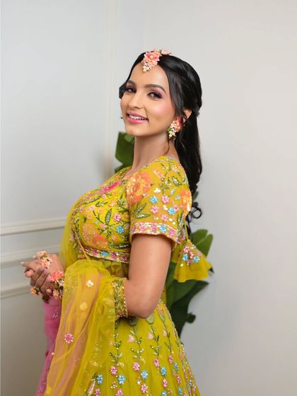 The bride looks radiant and happy in her colorful lehenga. The makeup is a perfect blend of natural and glam, ideal for daytime celebrations.