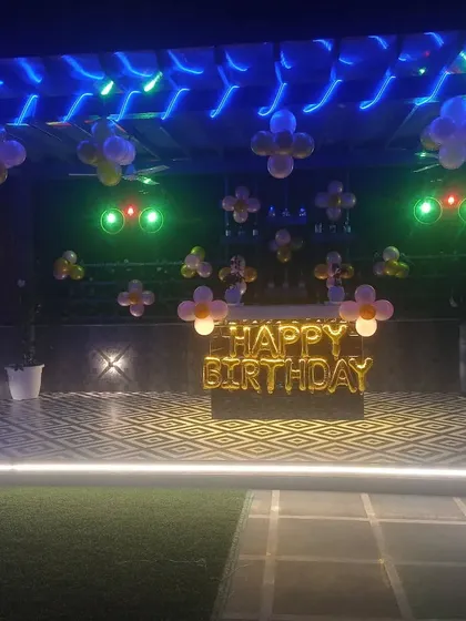 A simple rooftop birthday decoration. The "Happy Birthday" foil balloons are placed on a table, with small balloon clusters on the ceiling.