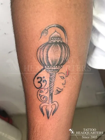 A powerful Hanuman Gada (mace) tattoo, integrated with symbols like the Trishul, Om, and a depiction of Hanuman's face.