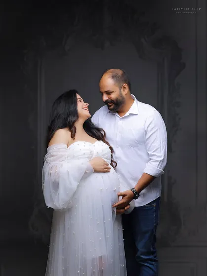 A loving glance between the couple. The classic white gown and shirt combination against a textured grey backdrop creates a timeless and elegant feel.