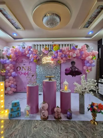 A glamorous "ONEderful" first birthday setup in shades of pink and purple. A silver shimmer wall, marquee "1," and an elegant balloon arch make this a perfect backdrop for a little princess.
