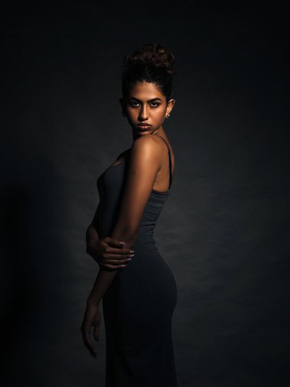 A three-quarter portrait with moody lighting that accentuates the model's strong pose and expression.