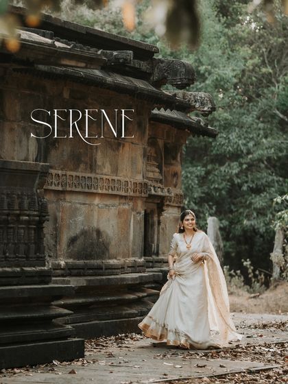 A serene portrait of the bride-to-be walking through a heritage site, her traditional white attire standing out beautifully against the rustic stone and fallen leaves.