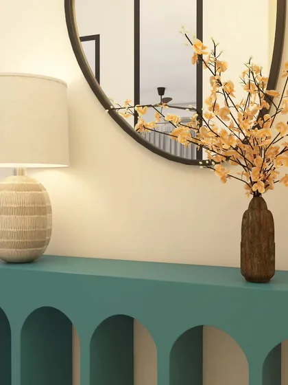 The entryway console sets the tone for the entire home. For this ATS Nobility foyer, we chose a striking teal console with arched details, paired with a simple round mirror and delicate floral arrangement to create a warm and stylish welcome.