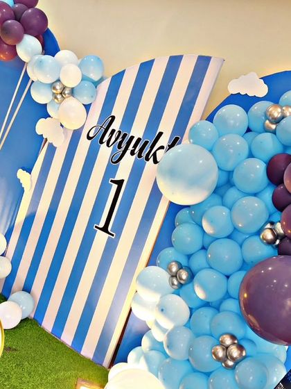 A close-up of a baby elephant-themed backdrop, featuring blue and white stripes and a '1' for the first birthday.