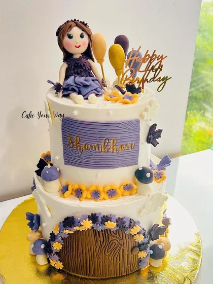 A custom two-tier fairy cake for a little angel, with a magical door and delicate floral details.