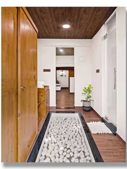 A unique bathroom design in a garden villa at Vijayshree Resort, Hampi, featuring a glass floor panel over a bed of white pebbles. This creative detail adds a spa-like and unexpected element to the space.
