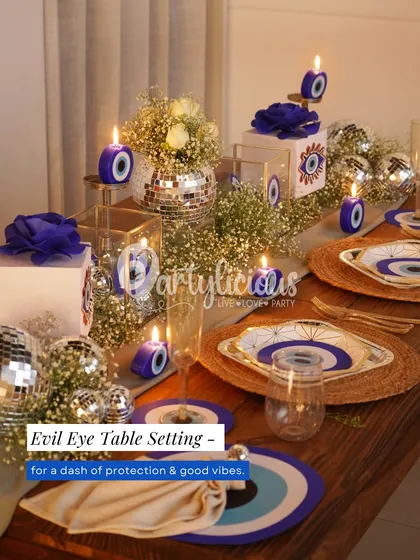 An Evil Eye table setting for a dash of protection and good vibes. This setup combines thematic plates and candles with disco balls and baby's breath for a modern, mystical feel.