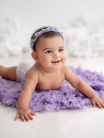 A baby girl enjoying tummy time on a fluffy purple rug.