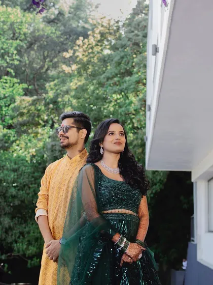 A stylish portrait of the couple posing back-to-back. Their modern ethnic wear and confident poses create a chic and contemporary image.