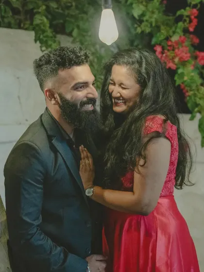 A candid shot of a couple sharing a laugh during their romantic, dimly lit pre-wedding night shoot.