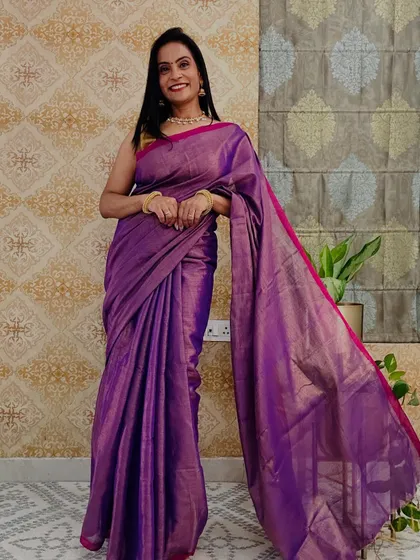 A rich purple tissue saree with a pink border. The jewel tone of this saree is stunning and perfect for an evening event.