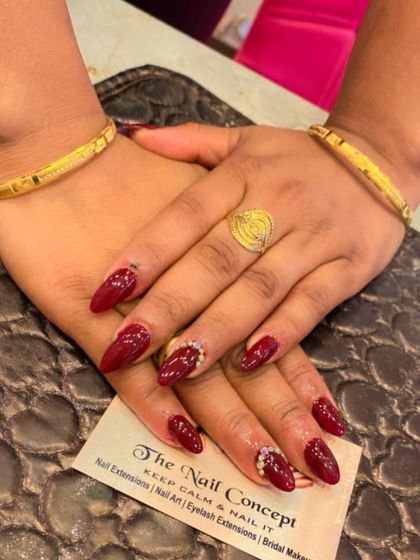 A sophisticated almond-shaped set in deep red. The ring fingers are accented with a delicate curve of small crystals along the side of the nail.