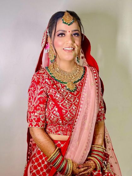 A beautiful bride in red with a soft pink dupatta. The makeup is fresh and dewy, perfect for her daytime ceremony.
