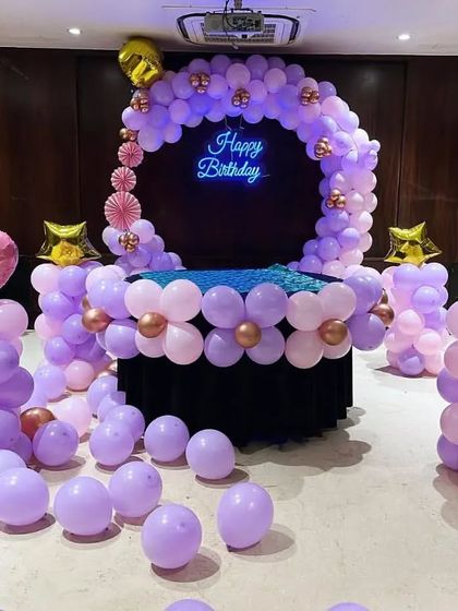 A lovely cake table decoration in pastel purple and pink, with a balloon ring and pillars topped with heart-shaped foil balloons.