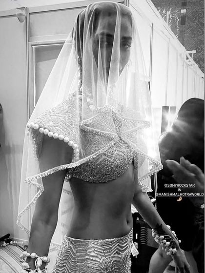 A black and white shot from backstage at the Manish Malhotra show, capturing the dramatic and timeless feel of the bridal couture look.