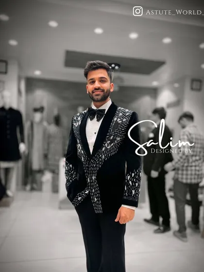 A client smiling in a black velvet tuxedo with abstract silver beaded patterns on the lapels and cuffs. This is a popular choice for reception and cocktail party attire.