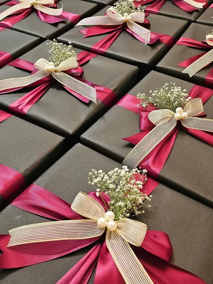 This is a great example of how I balance corporate identity with a touch of glamour. For a collaboration between Shoppers Stop and Axis Bank, I used a sophisticated dark grey wrap with bold magenta and cream satin ribbons, finished with delicate baby's breath and pearls. It's a chic and elegant look perfect for high-end corporate gifting.