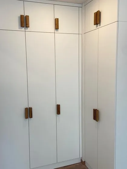 Inspired by clean Scandinavian design, this wardrobe combines matte white acrylic shutters with custom-made natural wood veneer handles. The result is a minimalist and highly functional storage solution that feels both modern and warm.