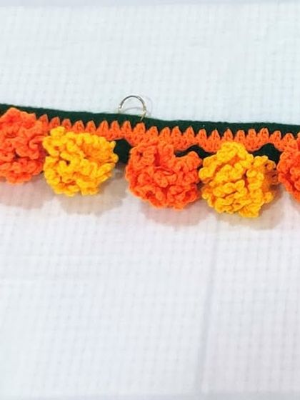 This design features a garland of orange and yellow marigold flowers with small hanging latkans for a playful touch.