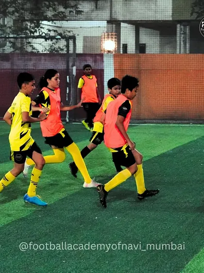 Players in bibs work on a team drill, focusing on passing and movement in a coordinated way.