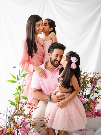 A candid moment of family love. This beautiful family portrait in shades of pink is full of sweet kisses and cuddles, capturing their natural connection in a light and airy setting.