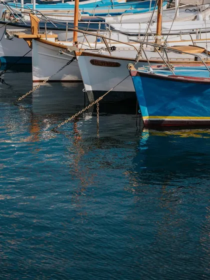 Classic wooden boats reflected in the calm harbor water of St. Tropez. The details and craftsmanship of the boats are a key part of the port's charm.