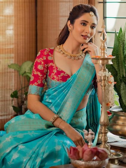 A festive look featuring a sky blue Kanchivaram saree paired with a contrasting pink blouse with floral embroidery. This combination is perfect for celebrations like Diwali.