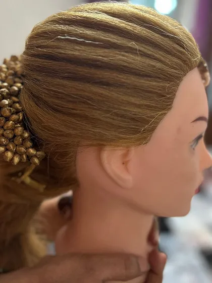 This practice style on a mannequin combines a textured ponytail with a sleek, wrapped base and a decorative bun accessory. It's a great example of the versatile party hairstyles we cover.