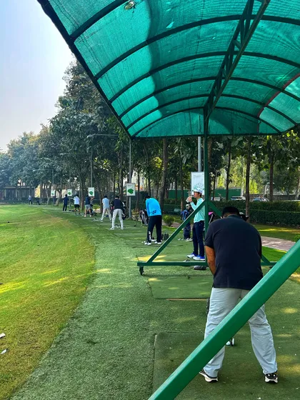 A view from behind the covered bays, showing a full range of golfers on a sunny day.
