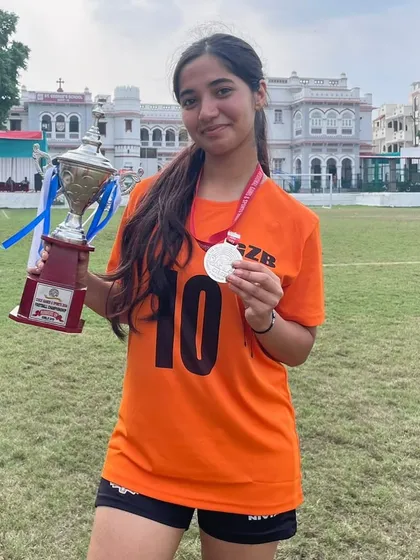 A player proudly displays her trophy and medal, a reward for her dedication and talent.